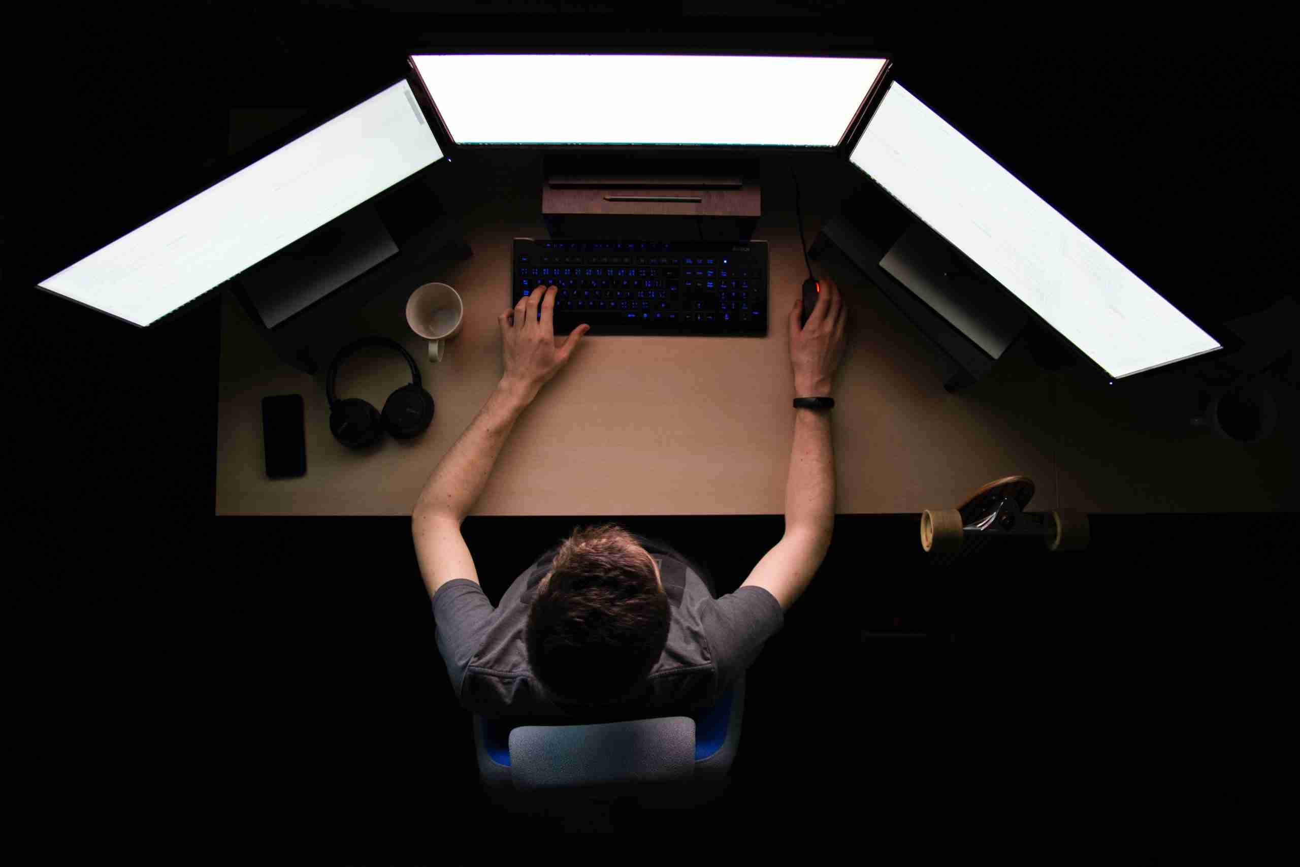 Man sitting in front of three monitors